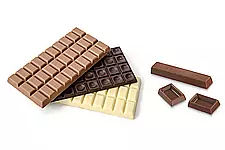 Three whole bars of chocolate lie next to a bar and two single pieces of chocolate