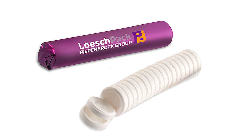Eine Rolle weiße gepresste Tabletten ohne Verpackung und eine Rolle mit lilafarbener Verpackung und LoeschPack Logo