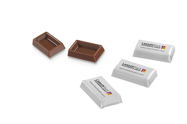 Zwei unverpackte Napolitains liegen links neben drei verpackten Schokoladentäfelchen