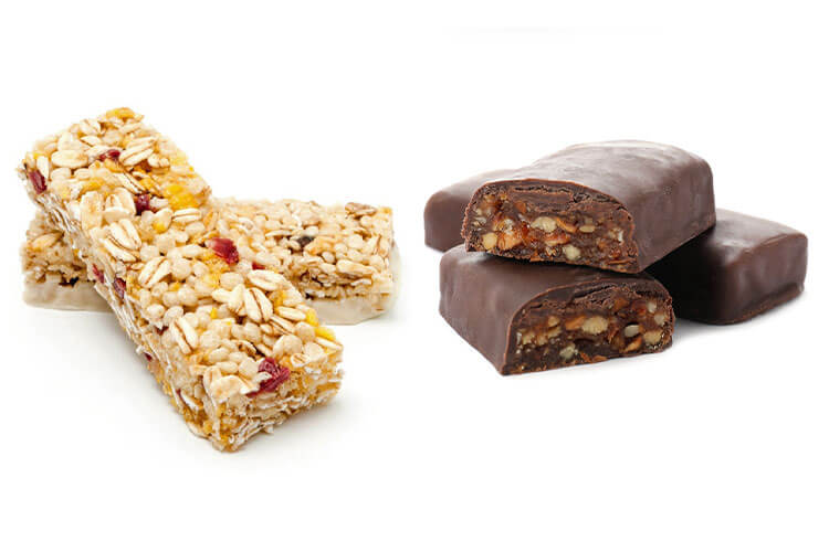 Verpackungslösung für Müsli- und Proteinriegel Zwei weiße Müsliriegel liegen aufeinandergestapelt neben drei dunklen Riegeln